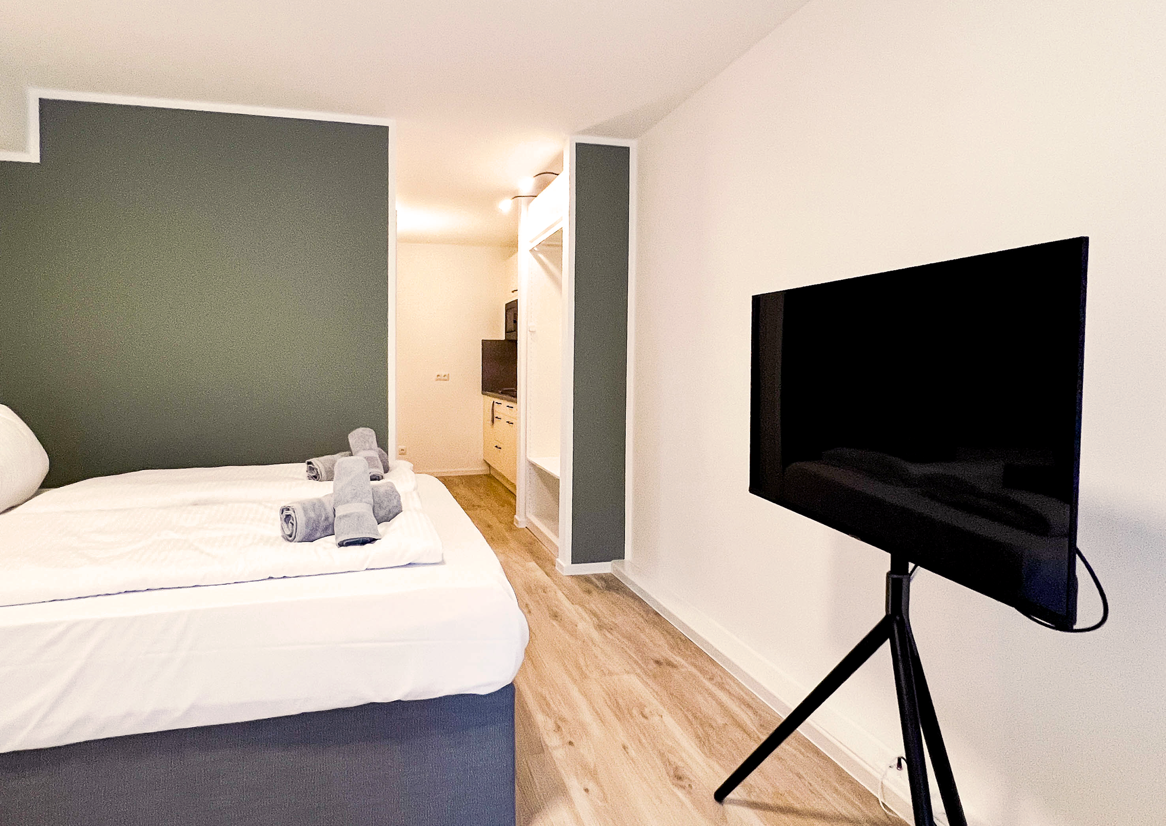 Doppelbett vor einem großen Smart TV
